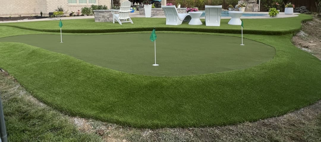 Backyard putting green, surrounded by lush artificial grass and outdoor seating area.